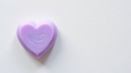 Obraz premium A delicately swirled lavender heart-shaped confection rests on a smooth, off-white surface, a symbol of affection and sweetness.