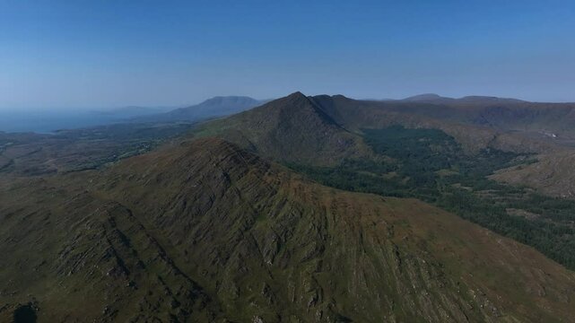 Sugarloaf, Caha Mountains, County Cork, Ireland, September 2024. Drone slowly pushes forwards with stunning aerial view of craggy peaks and forest, nature and rugged beauty of Irish landscapes.