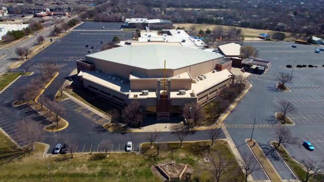 An aerial shot of a mega church with a huge cross in front of it.