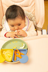new method of infant feeding. A six-month-old baby discovers self-feeding with pieces of fruit, vegetables and eggs. Concept: baby led weaning or BLW