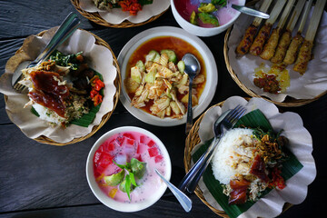 Set of nasi campur babi guling. Balinese meal of rice with Balinese roast pork and other side dishes of spicy fruit salads and mix ice. Top table view. Bali food. Indonesia food concept.