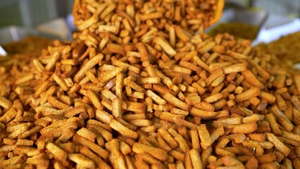 Crunchy breadsticks tumbling on metal conveyor in bakery process