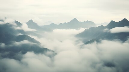 Obraz premium Majestic mountain range enveloped in a shroud of misty clouds and atmospheric fog creating a captivating and natural landscape