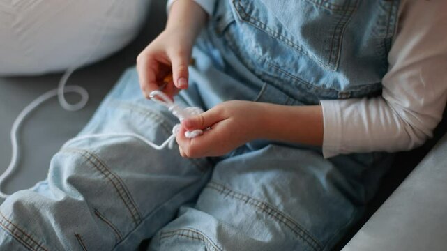 Child, learning crocheting, knitting, hand Crochet basics. Kid sitting at home, crocketing amigurumi figure