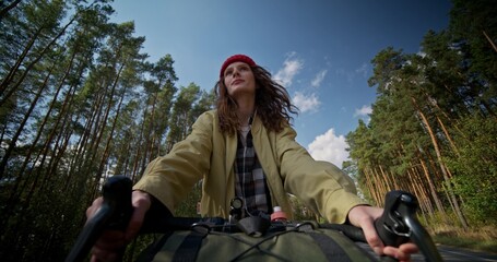 A woman rides a bicycle along the forest. Front view, close-up