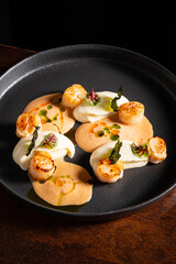 Savory Scallops Served on a Beautifully Arranged Plate With Creamy Sauces and Vibrant Garnishes at a Gourmet Restaurant