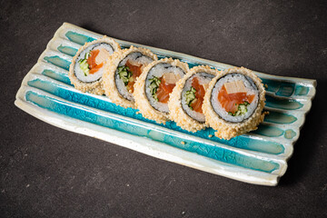 Sushi Rolls Carefully Arranged on a Unique Ceramic Plate, Showcasing Vibrant Colors and Textures Against a Dark Background in a Cozy Dining Setting