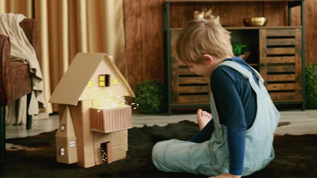 Child, cute boy, playing with toys in a playroom, teddy bear and little ducks with a paper house