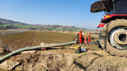A tractor's power take-off draws water from a canal and sends it to a sprinkler system, efficiently...
