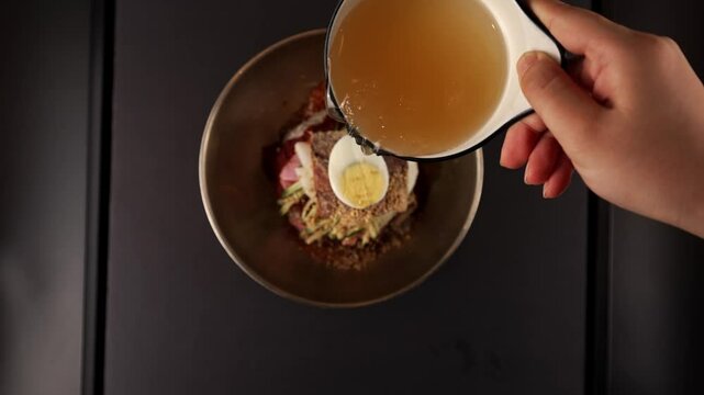 Chilled chewy noodles with savory pollock and a zesty kick. 고소한 명태와 새콤한 양념이 어우러진 차가운 쫄깃한 면.