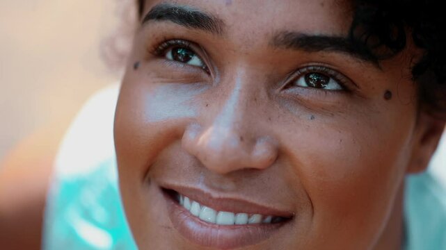 One hopeful young black woman looking at sky with FAITH and GRATITUDE. Close-up face of a joyful African descent person in 20s