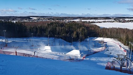 Snow-covered slopes with lampposts for skiers and snowboarders at the ski center have fencing for...
