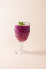 Purple blueberry smoothie in vintage glass with mint, highlighting texture and color on neutral background. Copy Space. Minimalist composition. Concept of healthy nutrition, antioxidants and freshnes