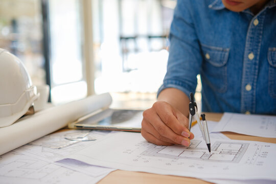 Architect designing house plans using a compass on a work desk