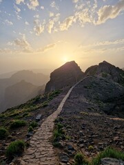 Obraz premium A stone path leading toward a majestic mountain peak at sunset, Pico do Arieiro, Madeira, Portugal
