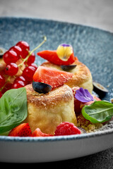 A vibrant and appetizing plate of Ukrainian syrniki, topped with fresh berries and a drizzle of sweet sauce.