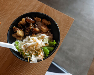 Blackpapper's fast food rice bowl consists of white rice, chicken pieces, vegetable salad, and a thick, savoury black pepper sauce served in a bowl.