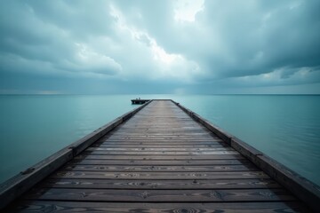 Fototapeta premium Empty wooden pier extends into a moody sea under a cloudy sky , grey, ocean, background