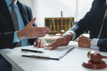 Two lawyers are reviewing and discussing contract details during a meeting in their office, with...