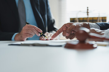Two lawyers are discussing a legal document, with one lawyer pointing to the signature line with...