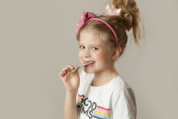 Adorable little girl eating sweet and sour colorful candy strip	