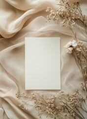 Flat lay of blank white wedding invitation card, surrounded by delicate silk fabric and dried flowers, with neutral color palette. Soft lighting, elegant and sophisticated atmosphere. View from above