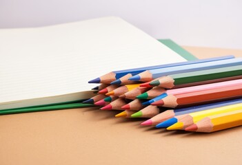Fototapeta premium Place colored pencils of various colors next to the notebook