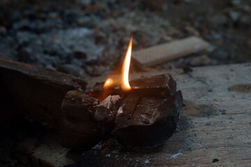 Bright flames ignite on a wooden base among scattered stones, highlighting the charm of fire in the dark.