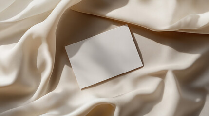 Blank white card mockup placed on textured beige fabric, perfect for showcasing wedding invitations, greeting cards, or event announcements with a neutral and sophisticated aesthetic