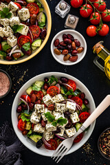 Greek style salad - fresh vegetables with feta cheese, kalamata olives on black table