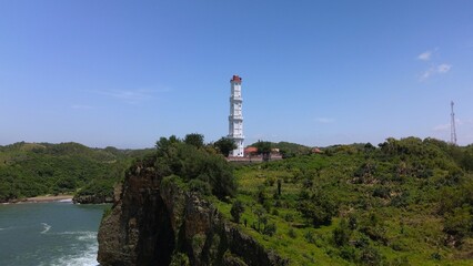 Aerial drone view Lighthouse on a coral hill on Baron beach, Gunung Kidul, Yogyakarta, which is also a tourist destination and traditional fishing port