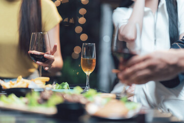 Obraz premium Sunset Cheers: Close-up view of friends enjoying wine and appetizers at an outdoor gathering, bathed in the warm light of the setting sun. The focus is on the drinks and food.