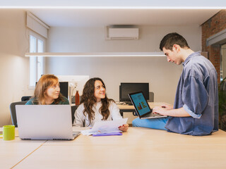 Group of young entrepreneurs working together in a casual coworking space. Concept of teamwork, innovation, and startup culture.