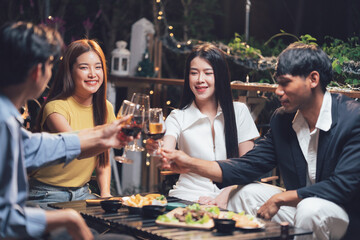 Cheers to Friendship: A group of young friends celebrate their bond with a toast, clinking glasses of wine and laughing as they savor a delicious meal outdoors.