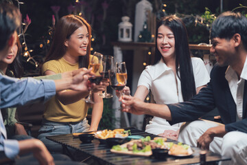 Nighttime Cheers: Friends raise their glasses in a toast, celebrating togetherness amidst warm lighting and delicious food, creating a scene of joyful camaraderie.