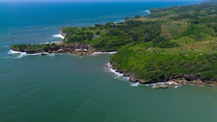 Fototapeta premium Bird eye view View of the coastline with hills and trees, cliffs, coral reefs and waves from the sea at Parang Ratjuk Gunung Kidul Yogyakarta
