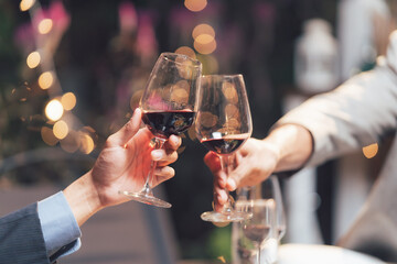 Cheers to Celebration: Two hands clink wine glasses filled with rich red wine, a romantic gesture against a backdrop of warm, twinkling lights. The image is a toast to friendship, love.