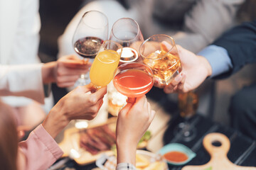 Cheers to Connection: Four hands raise glasses of wine, orange juice, and cocktails in a celebratory toast, a visual embodiment of friendship and shared joy.