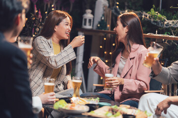 Nighttime Cheers: A group of friends raise their glasses in a toast, sharing laughter and conversation under the soft glow of twinkling lights on a warm summer night.  