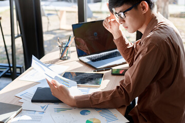 Side view of businessman analyzing financial reports in a bright digital office environment