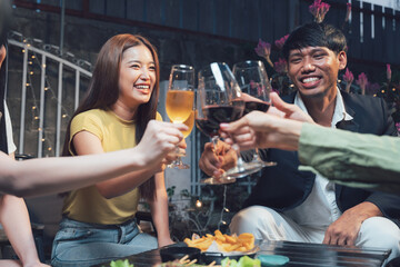 Nighttime Cheers: Friends raise their wine glasses in a toast, faces illuminated by warm lighting, enjoying a lively evening together.  The scene captures the joy of friendship and celebration.