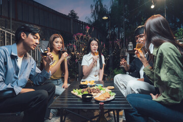 Nighttime Gatherings: A group of friends enjoy a casual and intimate dinner gathering outdoors,  sharing laughter, stories, and delicious food under the warm glow of string lights.  