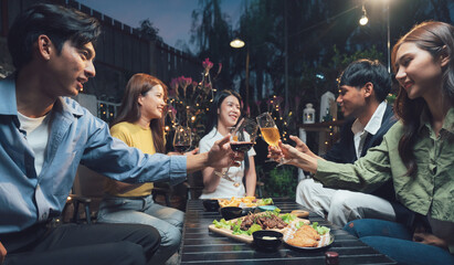 Nighttime Social Gathering: A group of young friends raise their glasses in a toast, enjoying a lively night out at an outdoor restaurant. Warm lighting and laughter fill the air.