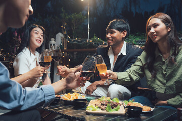 Nighttime Cheers: A group of friends raises their glasses in a toast under the soft glow of outdoor lights, creating a warm and inviting atmosphere of shared laughter and companionship.  