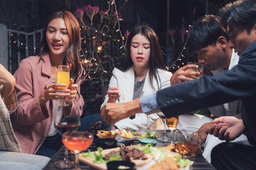 Nighttime Rendezvous: Friends enjoy a lively dinner and drinks at a chic restaurant, their laughter and conversation filling the warm, inviting atmosphere. 