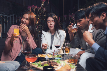 Night Out with Friends: A group of friends enjoys a festive night out, sharing laughter, conversation, and drinks over a table laden with delicious food.