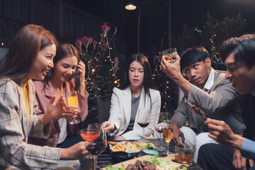 Nighttime Social Gathering: Friends enjoying a lively night out, sharing drinks, laughter, and good company around a table filled with food and drinks in a dimly lit, cozy setting.