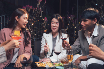 Nighttime Cocktails and Conversation: Friends enjoy a sophisticated evening gathering, clinking glasses and sharing laughter amidst a charming outdoor setting.