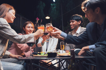 Nighttime Cheers: Friends raising glasses in a toast, celebrating together at a dimly lit restaurant or bar.  The image exudes warmth, friendship, and good times.