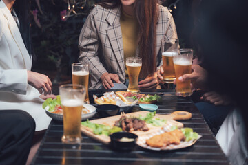 After-Work Drinks with Friends:  Friends gather around a table at a dimly lit restaurant, raising glasses of beer and sharing a hearty meal.